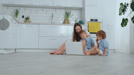 Beautiful-modern-young-family-lying-on-the-floor-at-home-and-doing-something-in-laptop